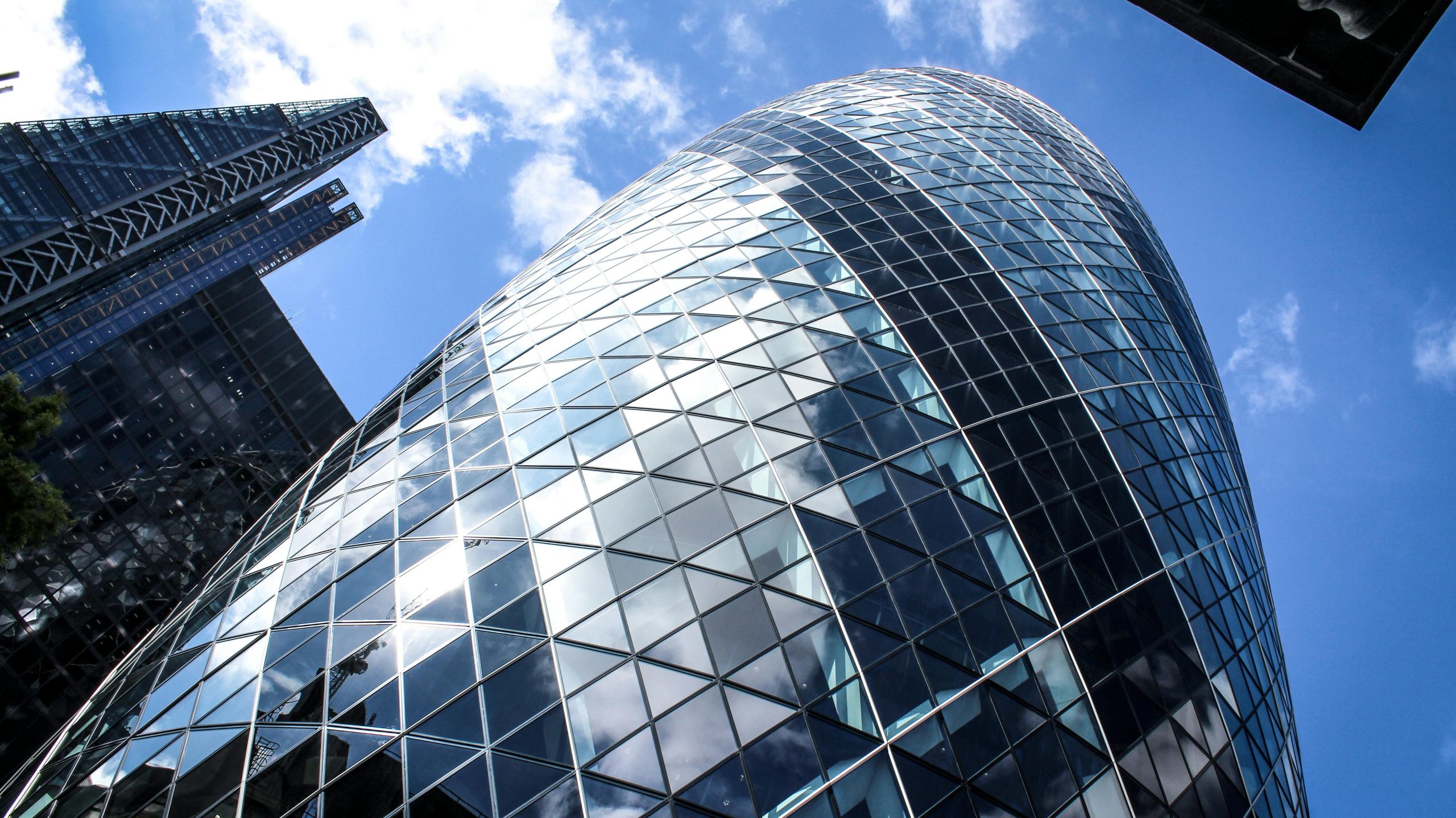 Low-angle shot of modern skyscrapers, featuring glass façades and a clear blue sky.