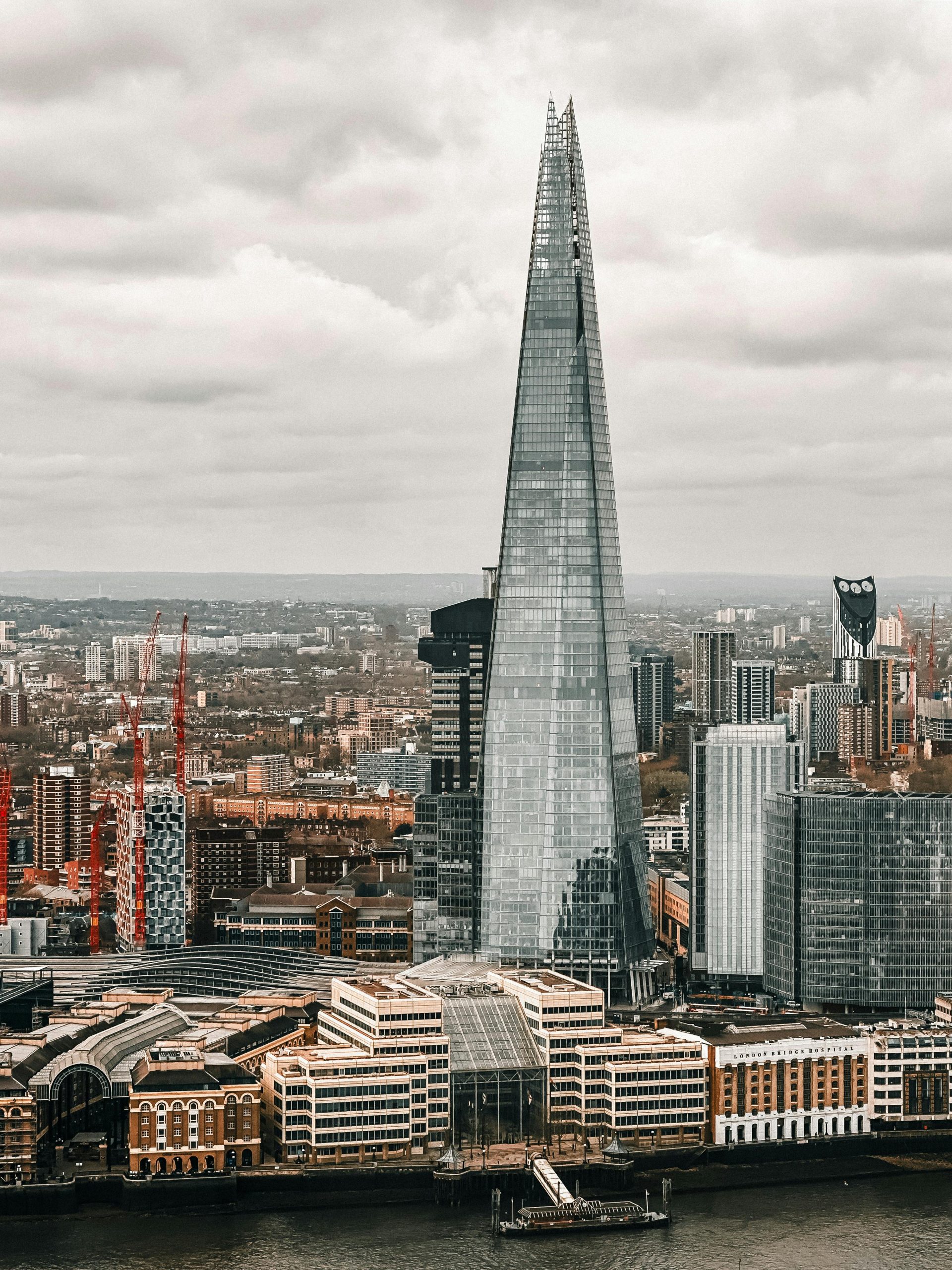 A stunning aerial shot of The Shard towering over London's urban skyline on a cloudy day.